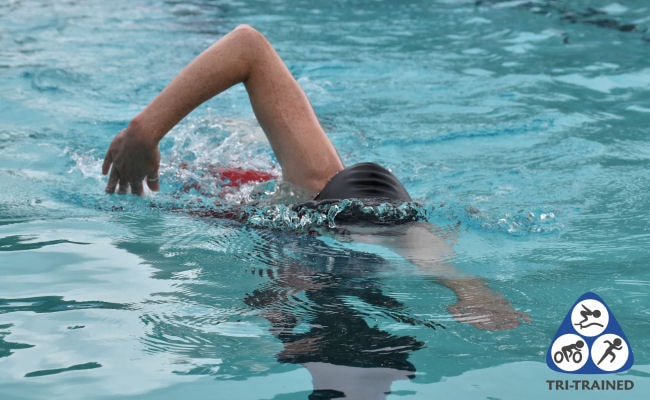 Swimmer doing Dribble swim drill in a red swimming costume in Sudbury