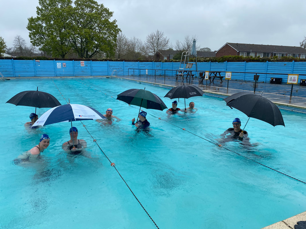swimmers sheltering from the rain in a swimming pool during triathlon training