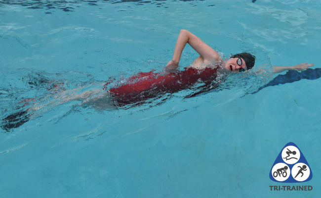 Swimmer doing sharkfin swim drill in a red swimming costume